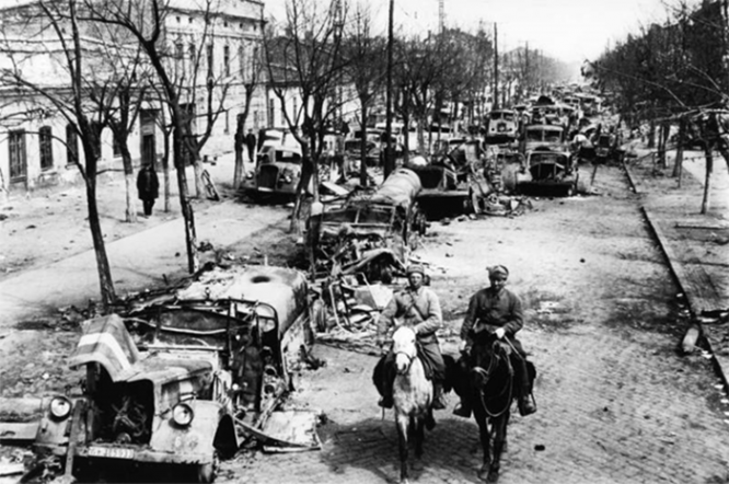 Советские солдаты едут по улице освобожденной Одессы, забитой брошенной немцами техникой