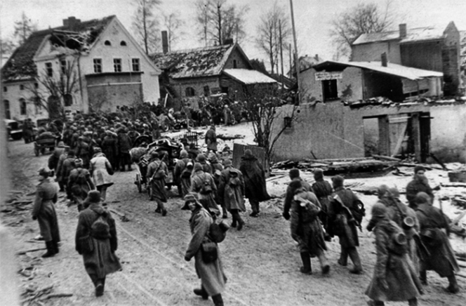 Советские солдаты проходят через немецкий населенный пункт на подступах к Кенигсбергу