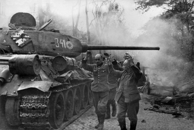 Советский танк Т-34-85 из 7-го гвардейского танкового корпуса и пленные ополченцы из фольксштурма на улицах Берлина, май 1945 г.